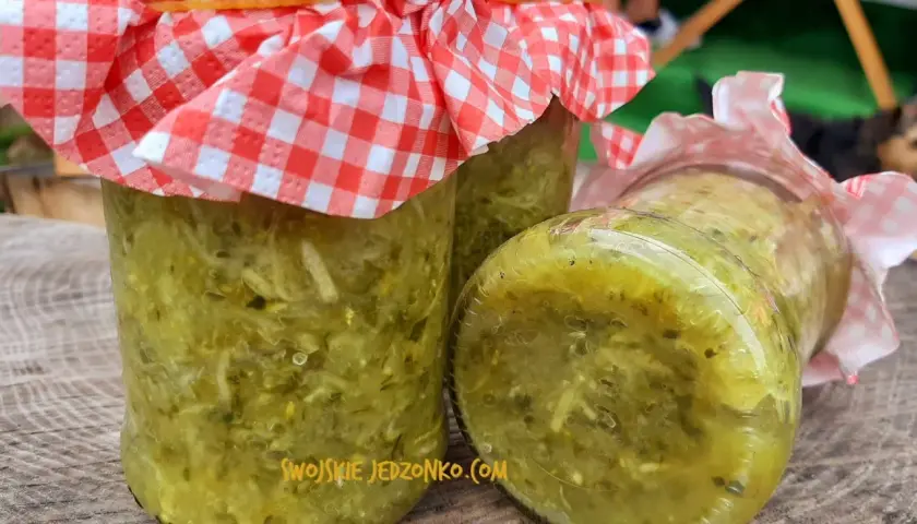 Słoiki z posiekanymi ogórkami na zupę ogórkową na zimę, przykryte kratkowanymi chusteczkami.