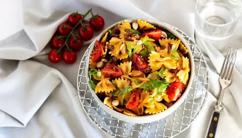 Mediterraner Salat mit getrockneten Tomaten und Rucola, garniert mit Mandeln und frischen Kirschtomaten. Ein köstliches Gericht.