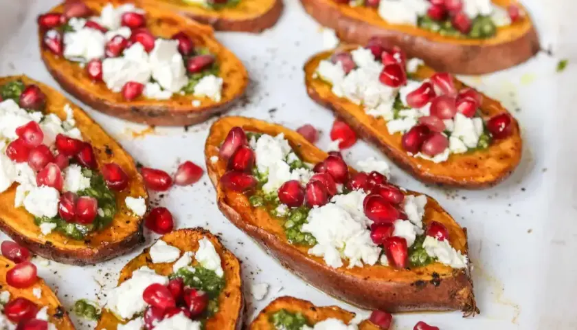 Pieczone bataty z piekarnika, udekorowane zielonym pesto, fetą i pestkami granatu. Pyszna przekąska!