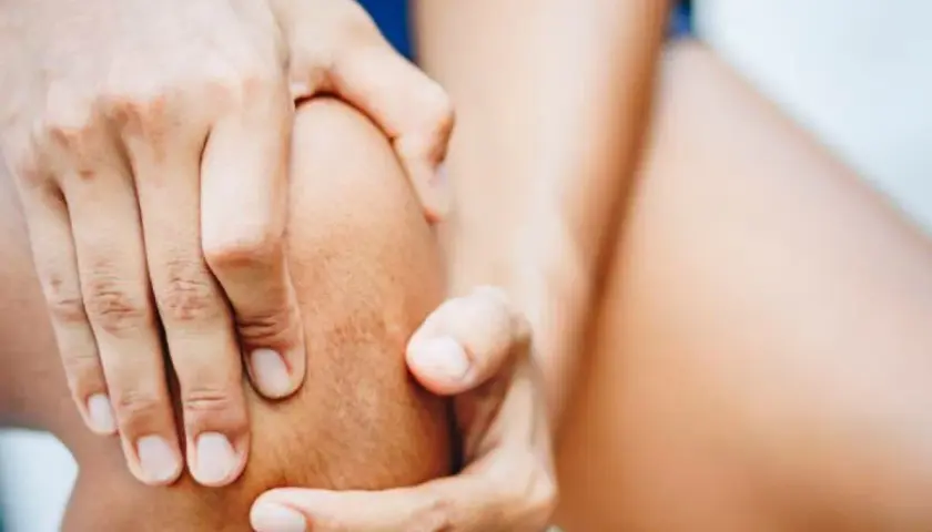 Hände umfassen ein Knie, das auf Schmerzen im Bereich des pes anserinus superficialis und profundus hindeutet.