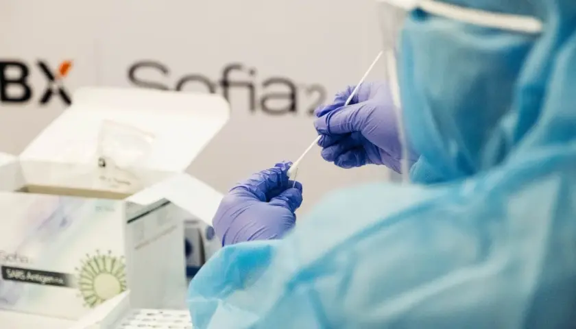 Osoba w kombinezonie i rękawiczkach przygotowuje testy Sofia SARS Antigen. To ważny kurs, który pomaga w diagnostyce.