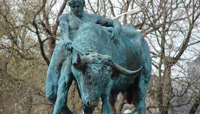 Sculpture d'un homme luttant avec un taureau, évoquant la force brute, comme le **logo Jupiler**.