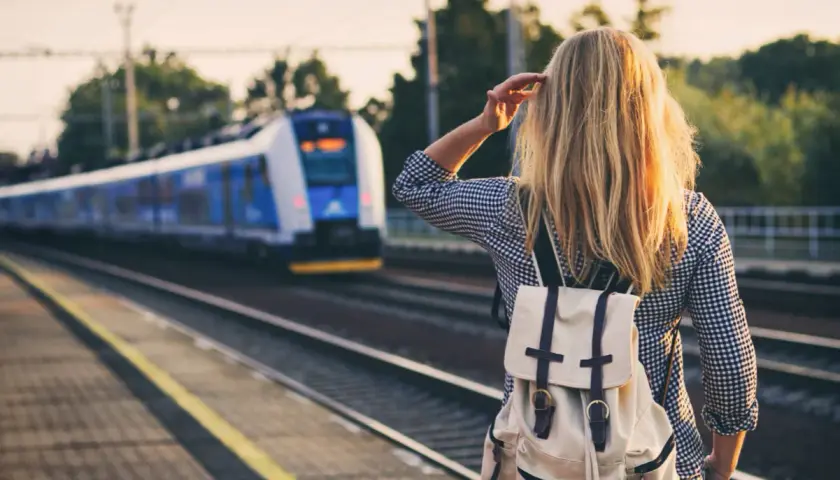 Dziewczyna z plecakiem czeka na pociąg, który zabierze ją do miast nad morzem.