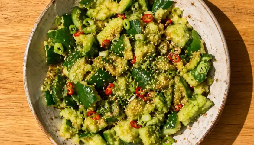 En skål med asiatisk gurksallad, toppad med sesamfrön, chili och salladslök. En fräsch och smakrik rätt.