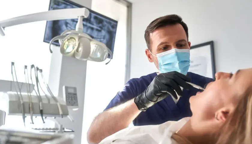 Dentista esamina un paziente, con un occhio attento alla salute orale. Un sorriso sano vale più di un bonus dentista 500 euro.