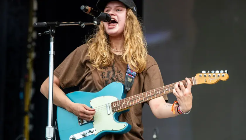 Mona på scen, sjunger och spelar gitarr med en blå Fender.