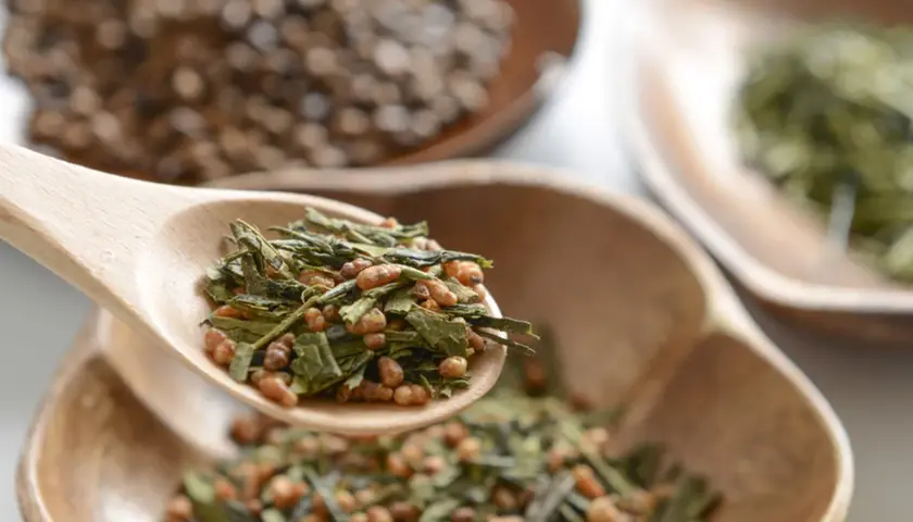 Holzschaufel mit Genmaicha Tee, dessen Wirkung durch gerösteten Reis und grünen Tee entsteht.
