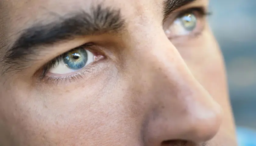Primer plano de los ojos de un hombre, destacando sus cejas pobladas y el iris azul verdoso.