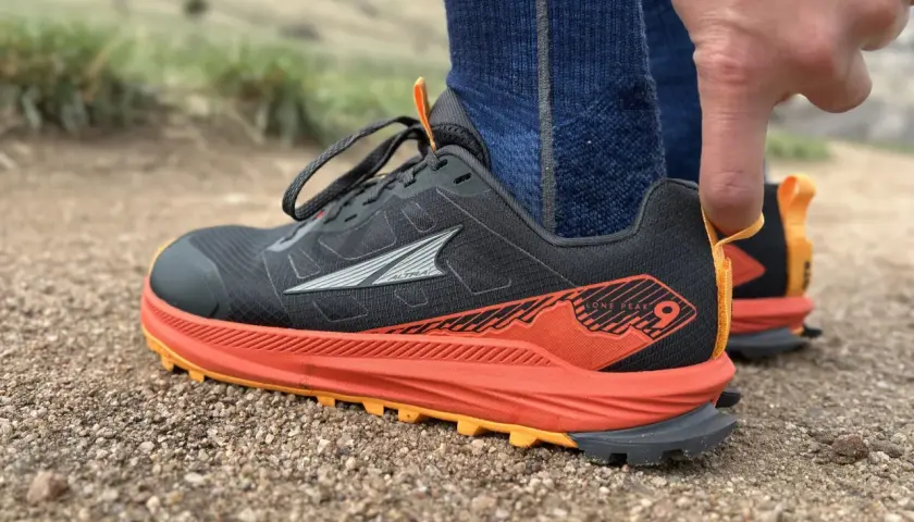 Close-up of a black Altra Lone Peak 9 trail running shoe with orange accents, ready for adventure.