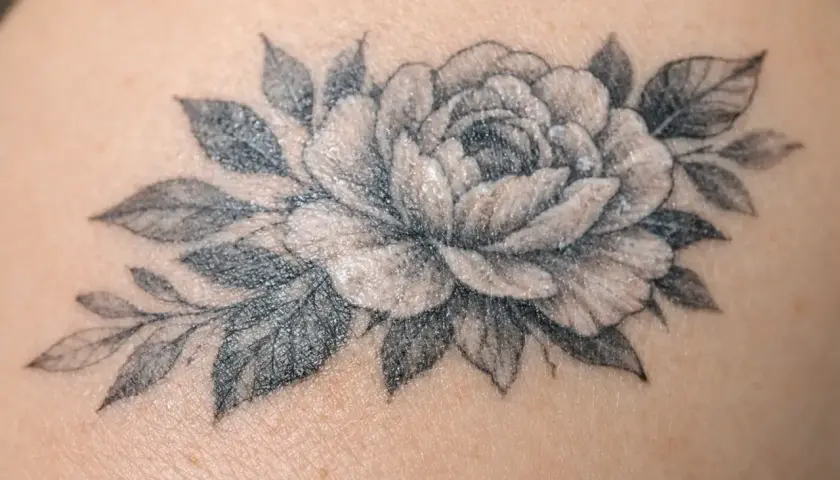 Un magnifique tatouage de pivoine et de feuilles, délicatement dessiné sur la peau.