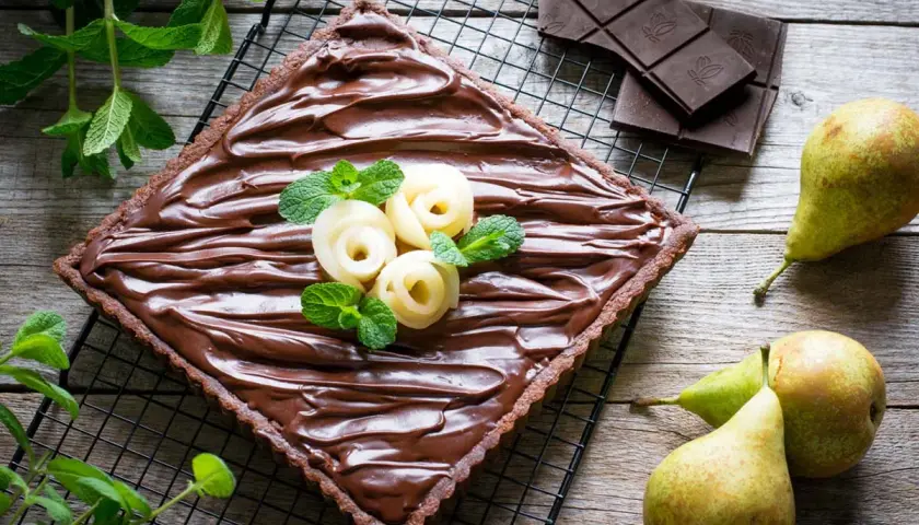 Torta quadrata al cioccolato con pere a rosa e menta. Un dolce goloso che unisce la cremosità della ricotta, la dolcezza delle pere e l'intensità del cioccolato.