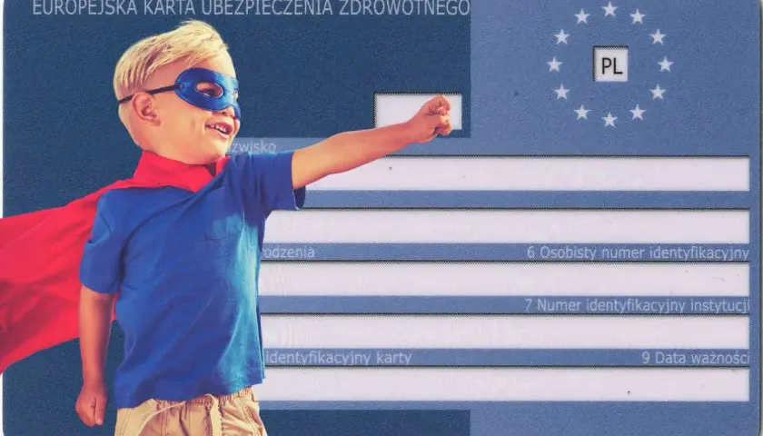 Mały superbohater w pelerynie i masce na tle Europejskiej Karty Ubezpieczenia Zdrowotnego. To ekuz dla dziecka, które czuje się bezpiecznie.