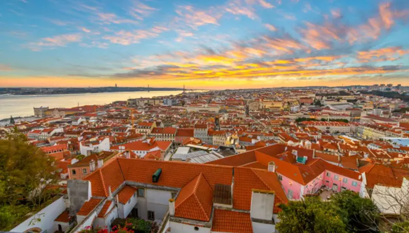 Un espectacular atardecer lisboa baña con tonos dorados y rosados el cielo sobre la ciudad y el río Tajo.