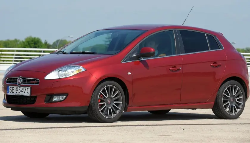 Czerwony Fiat Bravo 1.4 T-Jet z polskimi tablicami rejestracyjnymi SB 9547C zaparkowany na zewnątrz.