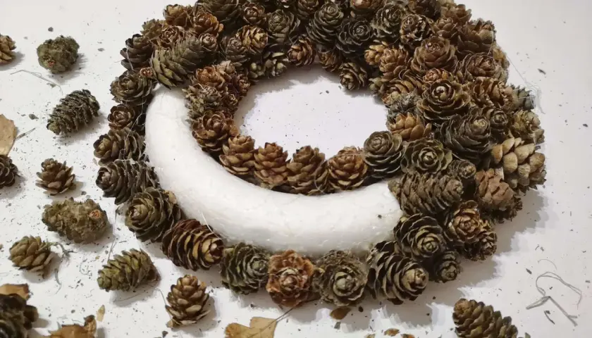 Ozdobny wianek z szyszek, idealny na ślubne dekoracje. Naturalne szyszki tworzą rustykalny urok.