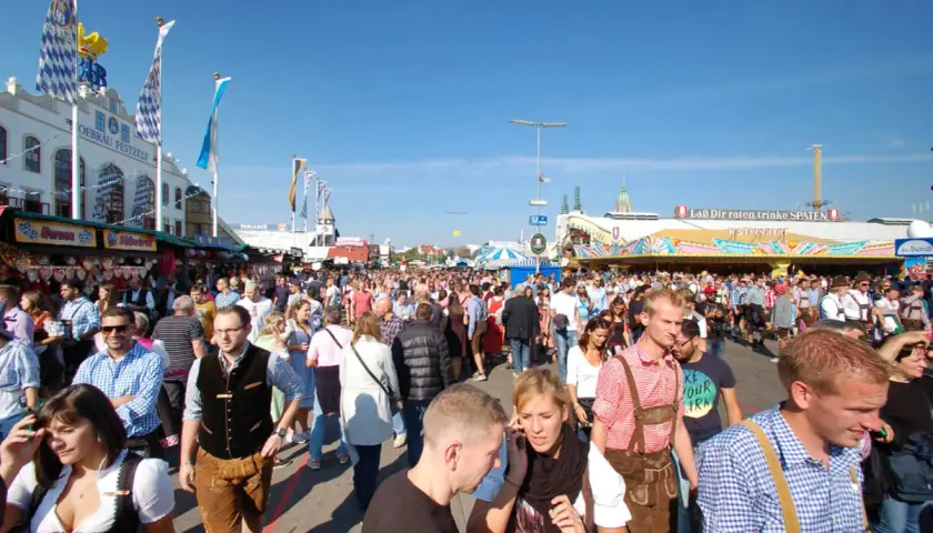 Menschenmassen auf dem Oktoberfest 2026, viele in Tracht, unter blauem Himmel.