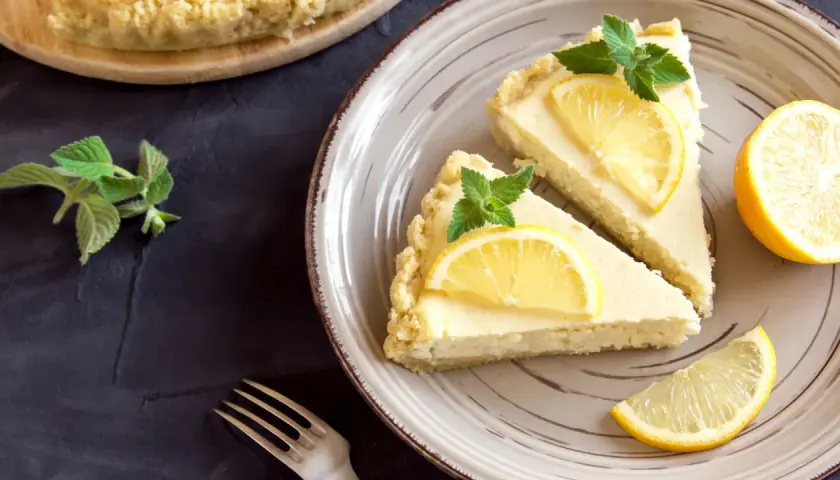 Dos porciones de tarta de limón, decoradas con rodajas de limón y hojas de menta, listas para ser disfrutadas.