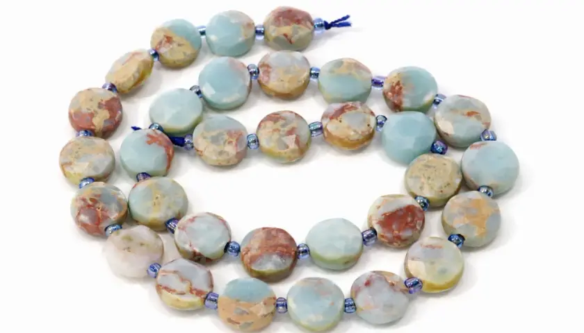Kette aus flachen, facettierten Scheiben aus grauem Jaspis mit blauen und roten Einschlüssen. Die Wirkung dieses Steins soll beruhigend sein.