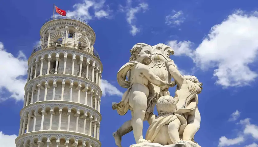 Kamienna rzeźba dzieci trzymających herb z napisem "PISA" na tle Krzywej Wieży w Pizie.