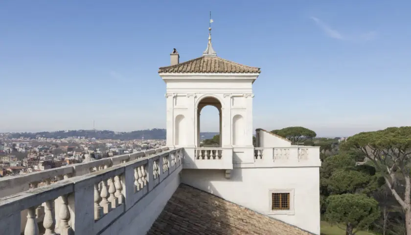 Vue panoramique de Rome depuis la Villa Médicis. Un belvédère blanc orné d'une arche domine le paysage urbain.