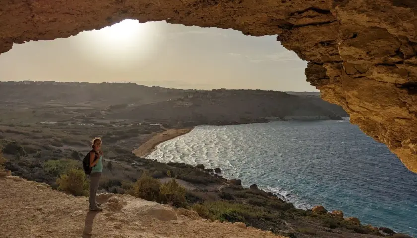 Frauenblick auf die Bucht von Malta im Dezember. Das Wetter ist mild, die Sonne scheint, und die Wellen brechen am Strand.