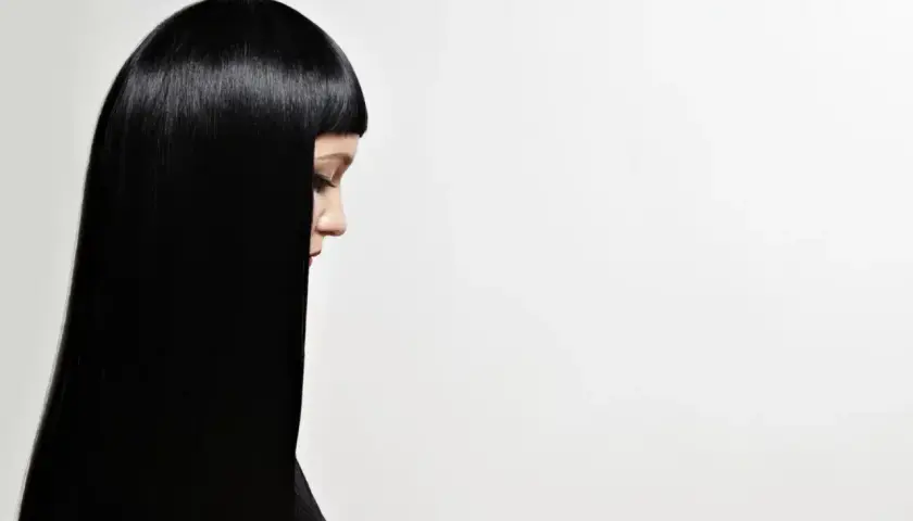 Perfil de mujer con cabello liso y brillante, negro azabache, cayendo sobre su hombro.