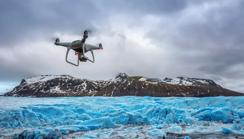 Dron rejestruje spektakularne zdjęcia lodowca o intensywnie niebieskiej barwie, z ośnieżonymi górami w tle.
