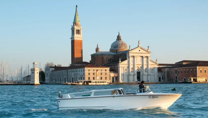 Taxi boat naviguant sur le Grand Canal, avec l'église San Giorgio Maggiore en arrière-plan. Idéal pour connaître le tarif taxi Venise.