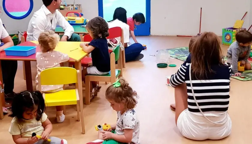 Niños jugando y un adulto observando, parte de lo que es el periodo de adaptación en un aula.