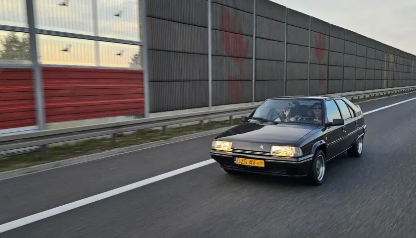 Czarny Citroën BX z zabytkowymi tablicami rejestracyjnymi jedzie autostradą.