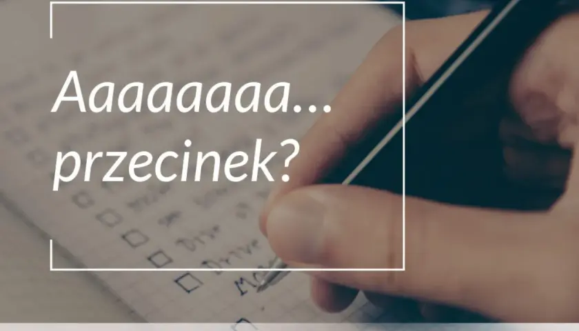 Długa litera "a" i pytanie "przecinek?" na tle notatnika, gdzie ręka pisze długopisem.