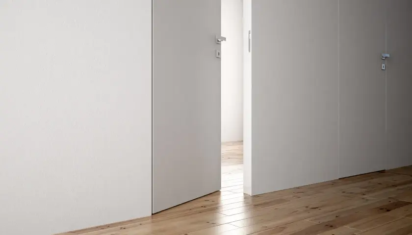 Parete di cartongesso con porta a battente aperta, che rivela un corridoio con parquet.