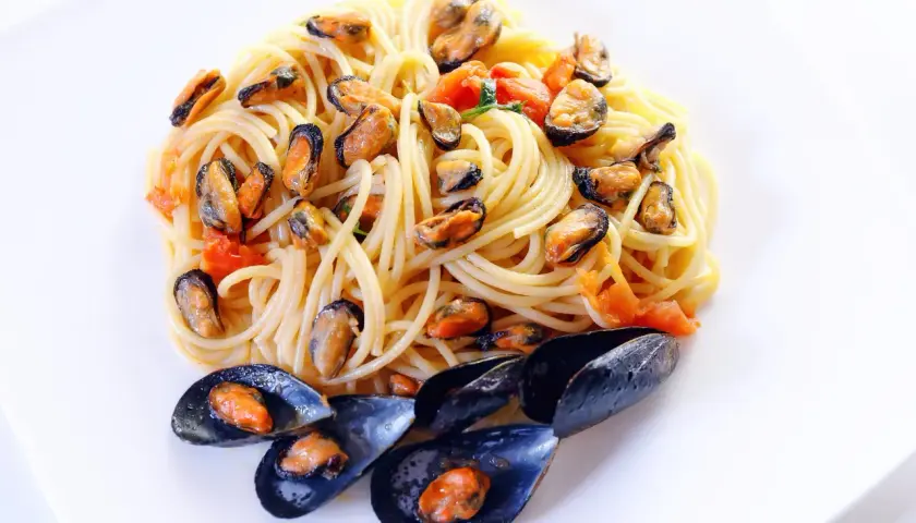 Spaghetti alla tarantina con cozze e pomodorini, un piatto di mare saporito e colorato.