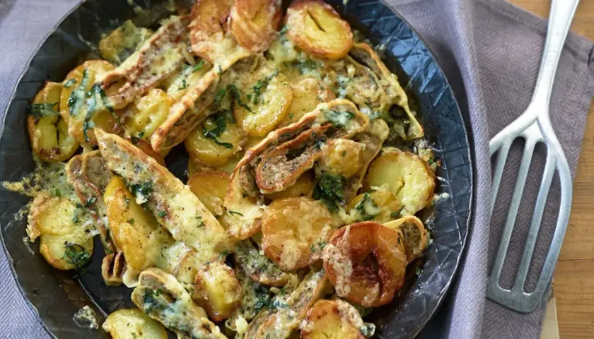Herzhafte Maultaschen-Pfanne mit goldbraunen Kartoffelscheiben und geschmolzenem Käse, garniert mit frischen Kräutern.