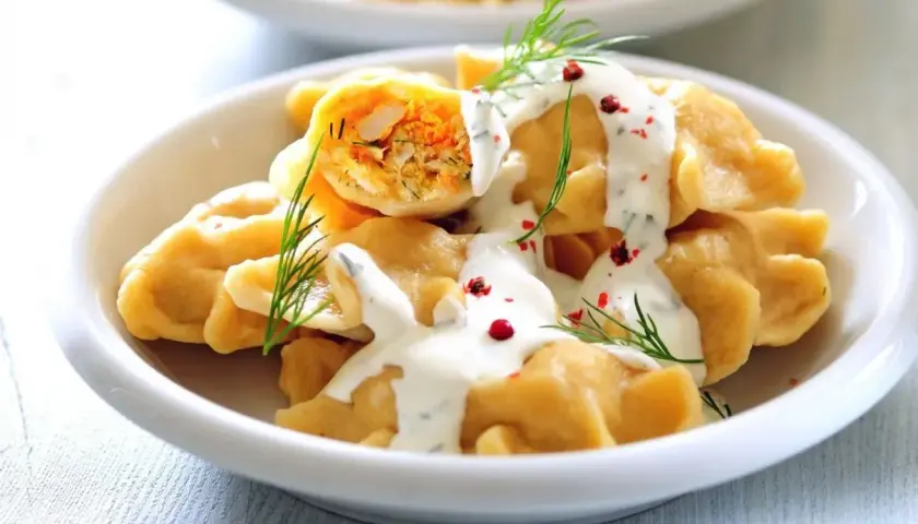 Pyszne pierogi z farszem, polane śmietaną i posypane koperkiem i pieprzem. Idealny obiad na sobotę.