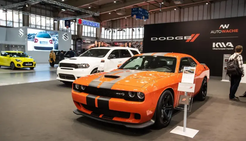 Pomarańczowy Dodge Challenger SRT na wystawie, obok białego Durango. Sprawdź dodge challenger cena i dostępne modele.