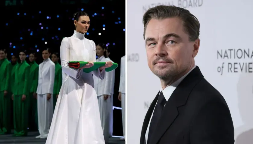 Leonardo DiCaprio na gali National Board of Review, obok modelki w białej sukni i grupy osób w zielonych strojach.