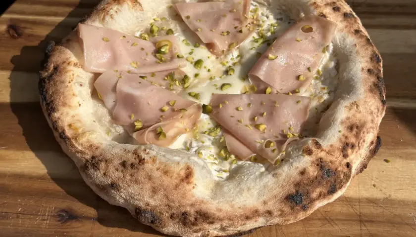 Neapolitanische Pizza mit Mortadella und Pistazien. Die perfekte neapolitanische Pizza Temperatur sorgt für einen luftigen Rand und geschmolzenen Käse.