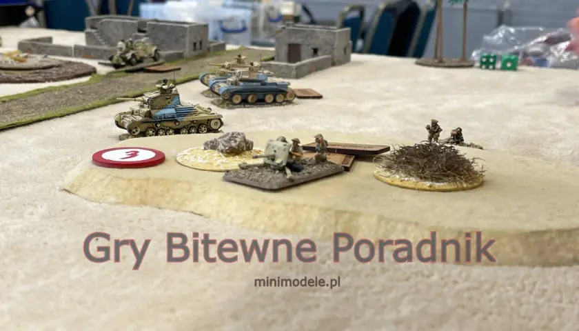 Miniaturowe czołgi i żołnierze na pustynnym polu bitwy. Sceneria do figurkowych gier bitewnych.