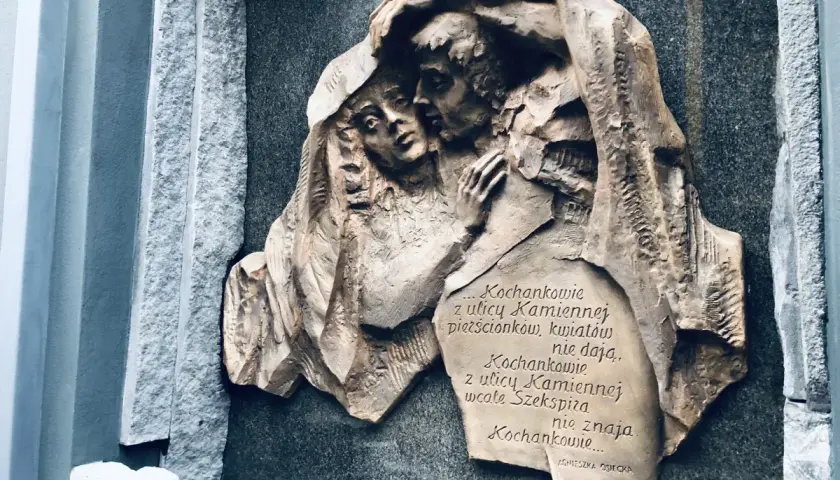 Rzeźba na kamiennej płycie przedstawia przytulonych kochanków. Cytat z Agnieszki Osieckiej mówi o miłości z ulicy Kamiennej.