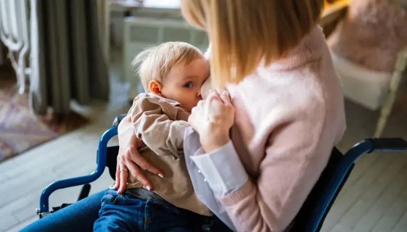 Mama w wózku karmi piersią dziecko. Decyzja o rezygnacji z karmienia piersią może być trudna, ale miłość pozostaje.