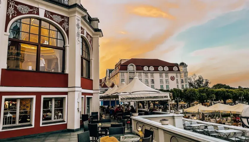 Eleganckie tarasy z widokiem na morze, idealne na kolację w jednej z nowych restauracji w Gdańsku. Zachód słońca maluje niebo na pomarańczowo.
