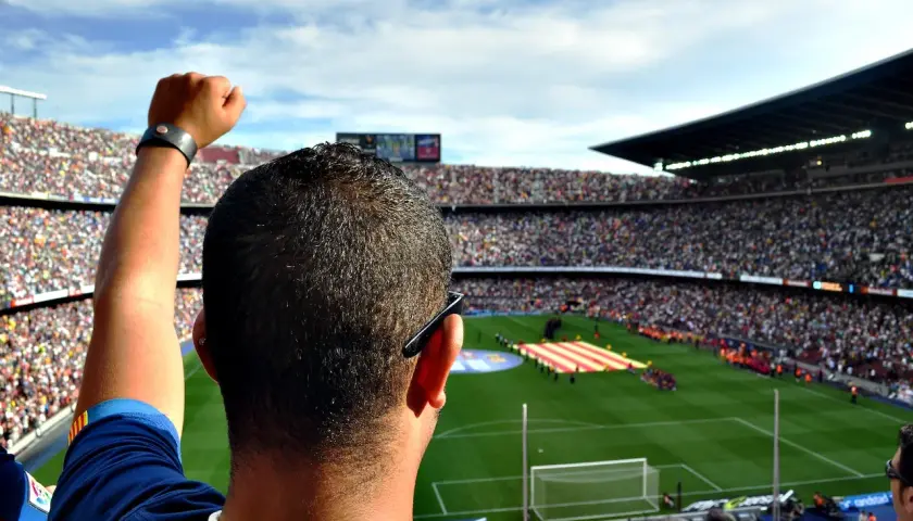 Kibic z podniesioną pięścią na stadionie, dumny jak właściciel Barcelony.