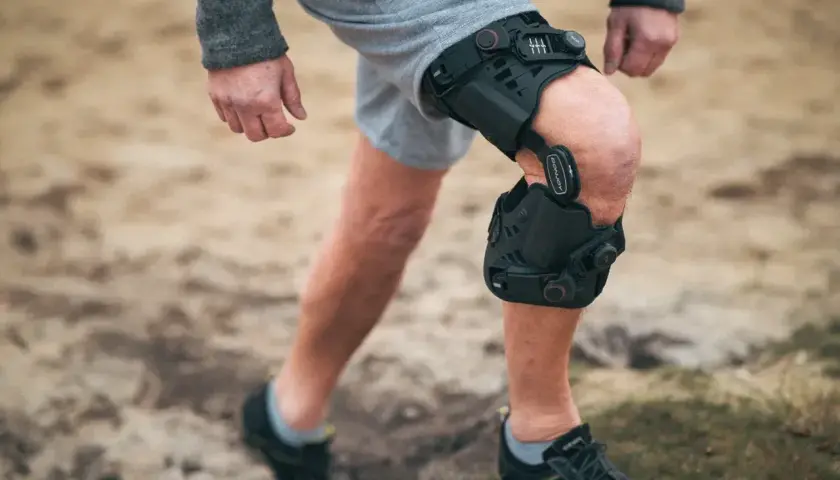 Mann mit Knieorthese, die bei einem Innenbandriss am Knie hilft.