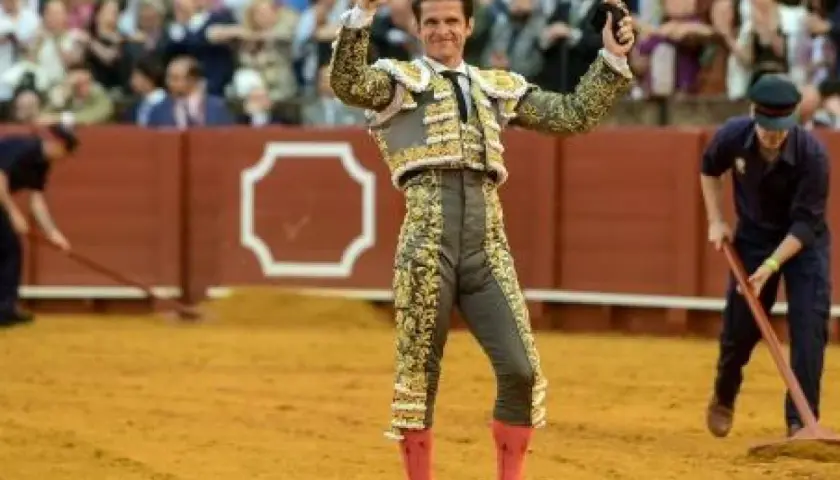 El Juli, torero con traje de luces, levanta las manos en la arena.