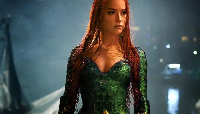 Amber Heard w zielonym kostiumie z filmu "Aquaman". Jej długie, rude włosy opadają na ramiona.