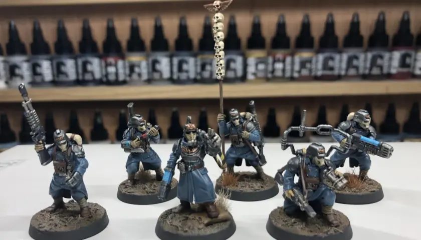 Krieg command squad w niebieskich mundurach, z karabinami i sztandar z czaszkami, gotowi do walki.