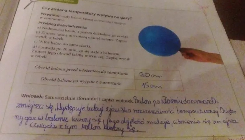 Niebieski balon i fragment ręki trzymającej taśmę mierniczą na tle tekstu o doświadczeniu.