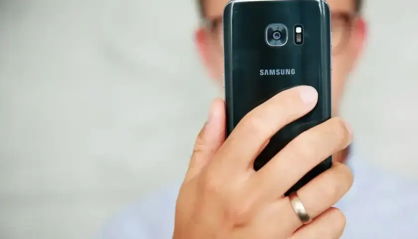 Osoba trzyma czarny telefon Samsung, pokazując tył z aparatem. Dowiedz się, jak poprawić jakość aparatu w telefonie Samsung.