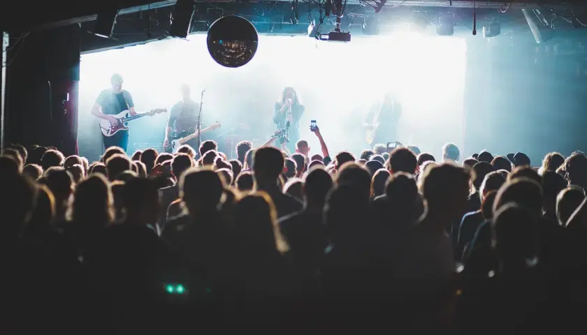 Publik njuter av en konsert i Stockholm idag. Bandet spelar på scenen medan publiken filmar med sina mobiler.